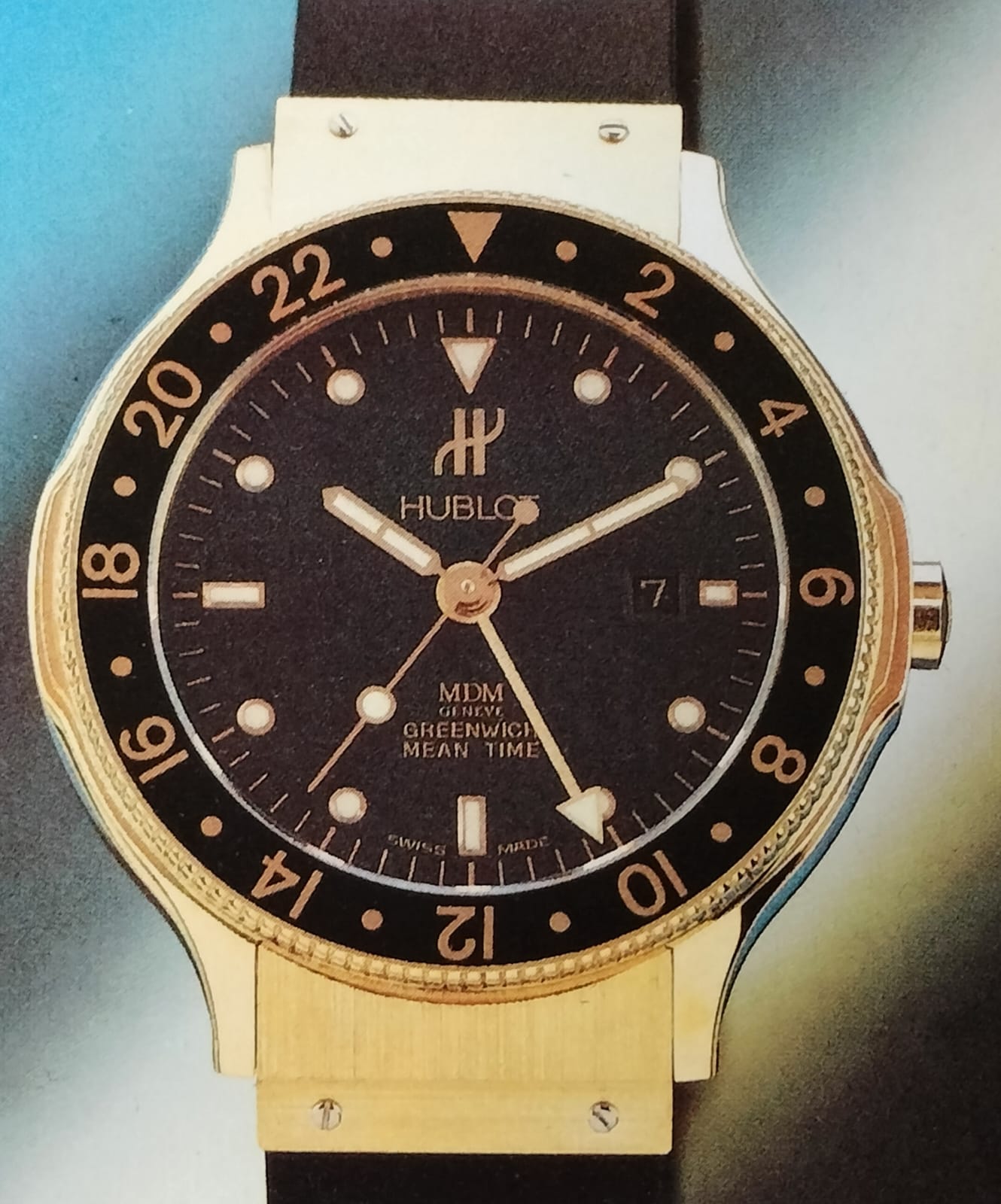 An early-1990s Hublot GMT in yellow gold with a black dial and a black rubber strap, signed MDM Genève — the gold-and-rubber formula the Classic Fusion Tributo revisits